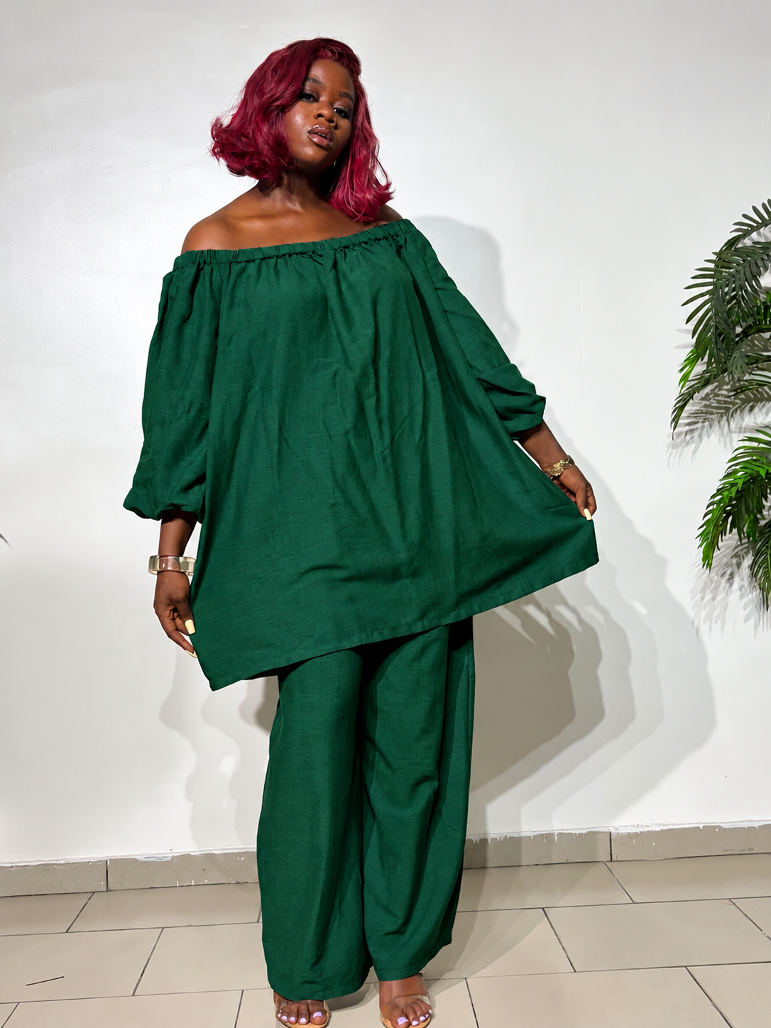 Elegant two-piece outfit featuring an off-shoulder tunic top with statement puff sleeves and matching wide-leg trousers, styled for a classy look.