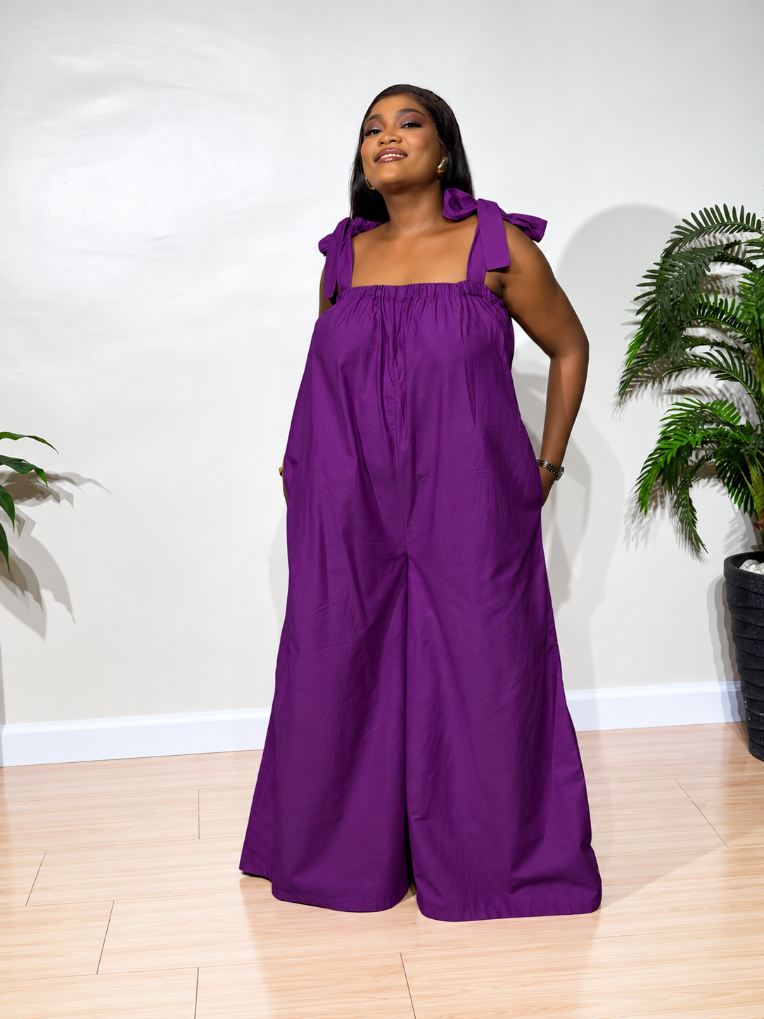 Solara jumpsuit with a gathered neckline, statement shoulder ties, and flowy wide-leg trousers, styled for effortless elegance.