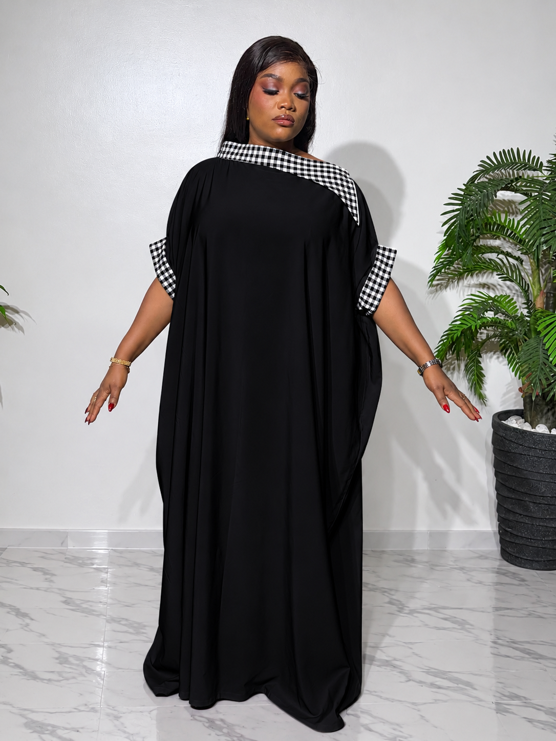 Elegant Black boubou with black and-white checkered accents, featuring a flowing silhouette, statement cape sleeves, and a luxurious finish.