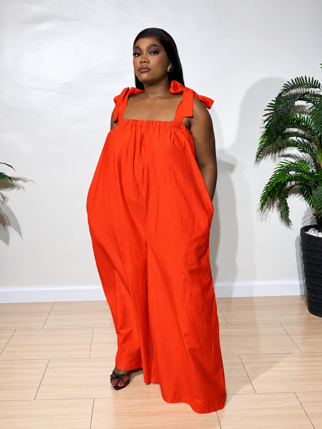 Solara jumpsuit with a gathered neckline, statement shoulder ties, and flowy wide-leg trousers, styled for effortless elegance.