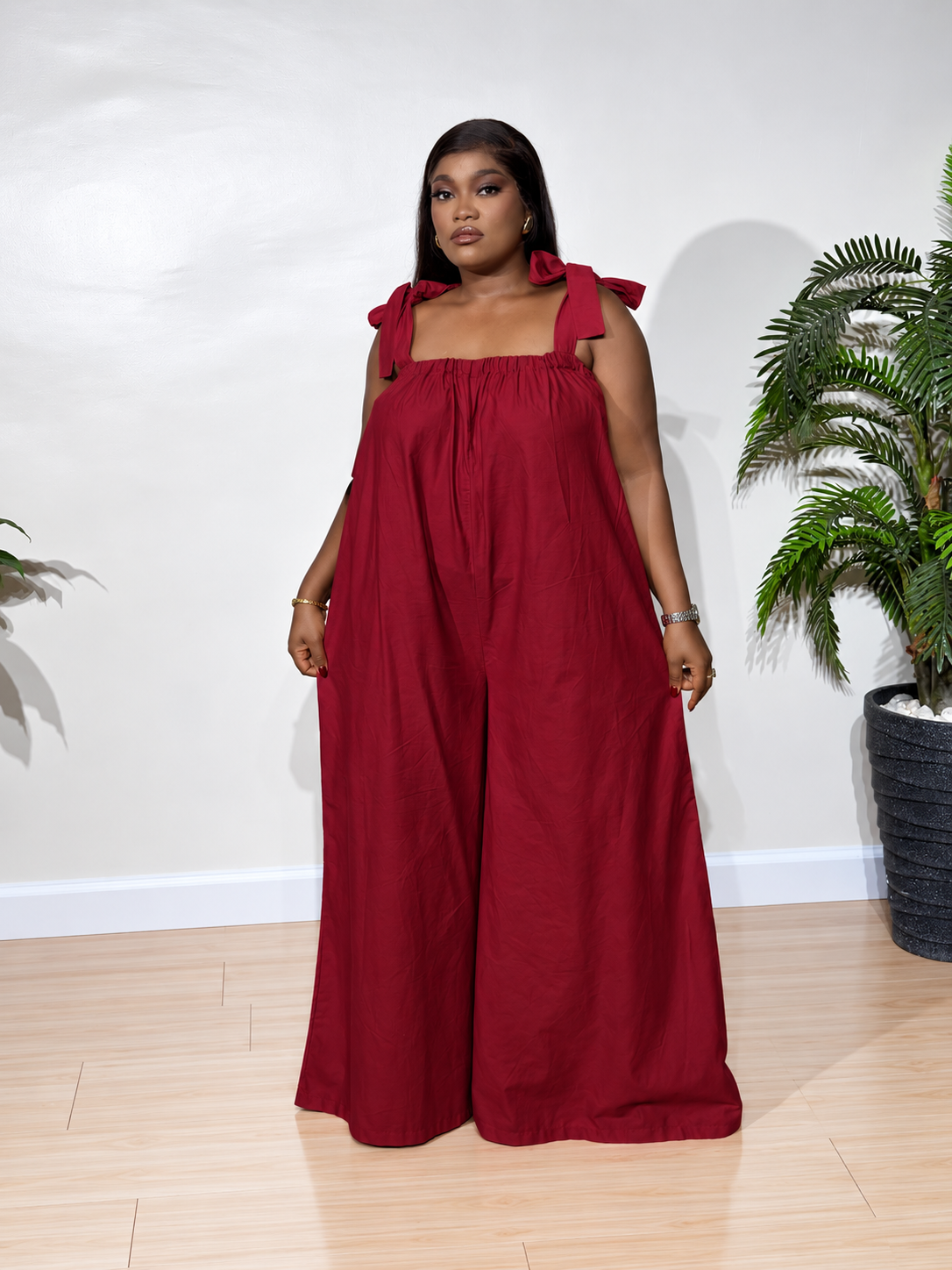 Solara jumpsuit with a gathered neckline, statement shoulder ties, and flowy wide-leg trousers, styled for effortless elegance.