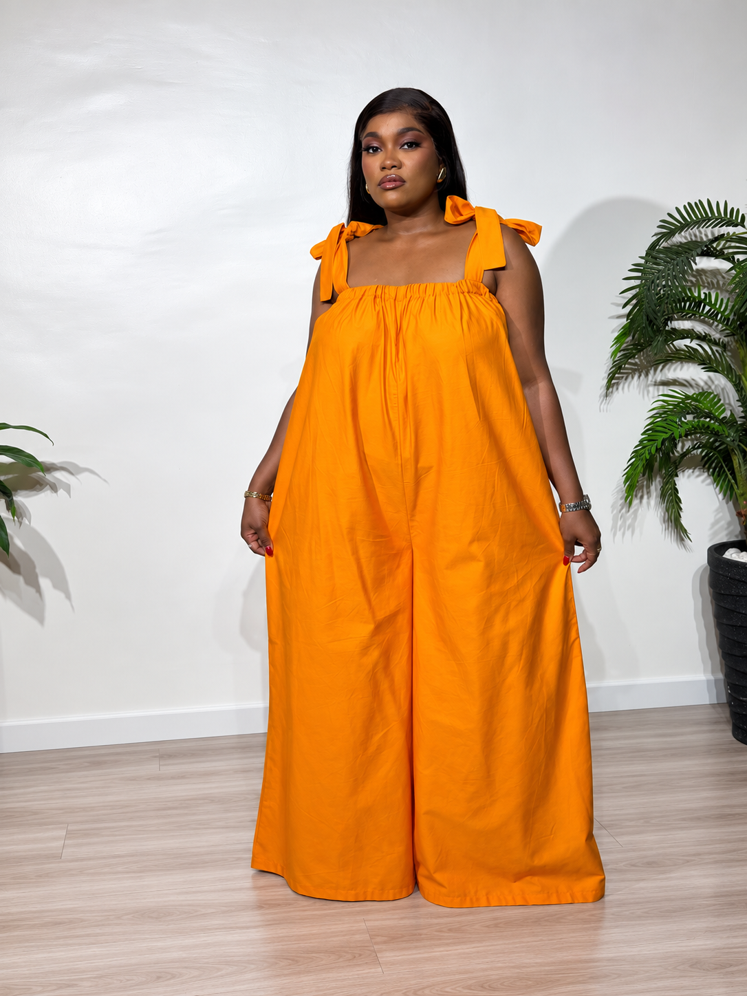 Solara jumpsuit with a gathered neckline, statement shoulder ties, and flowy wide-leg trousers, styled for effortless elegance.