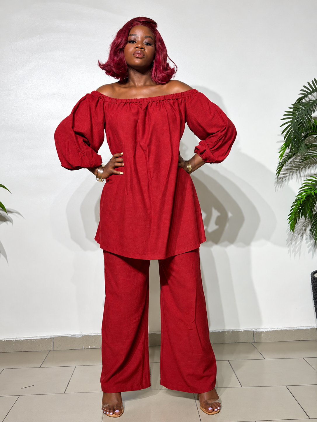 Elegant two-piece outfit featuring an off-shoulder tunic top with statement puff sleeves and matching wide-leg trousers, styled for a classy look.