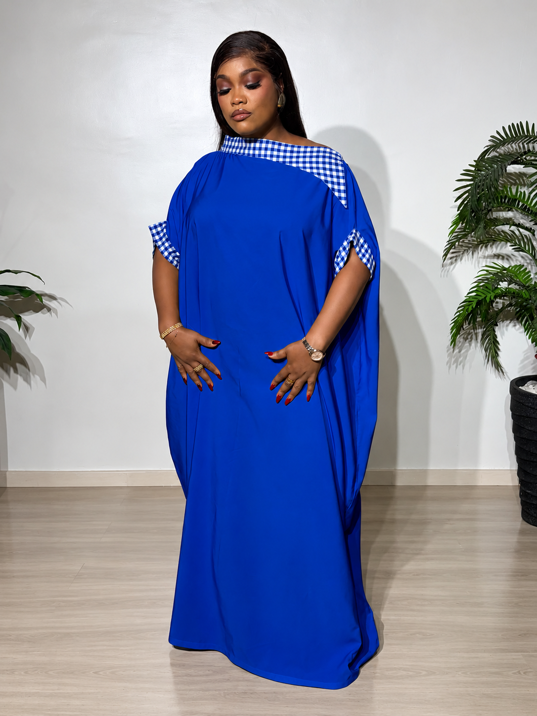 Elegant blue boubou with blue-and-white checkered accents, featuring a flowing silhouette, statement cape sleeves, and a luxurious finish.