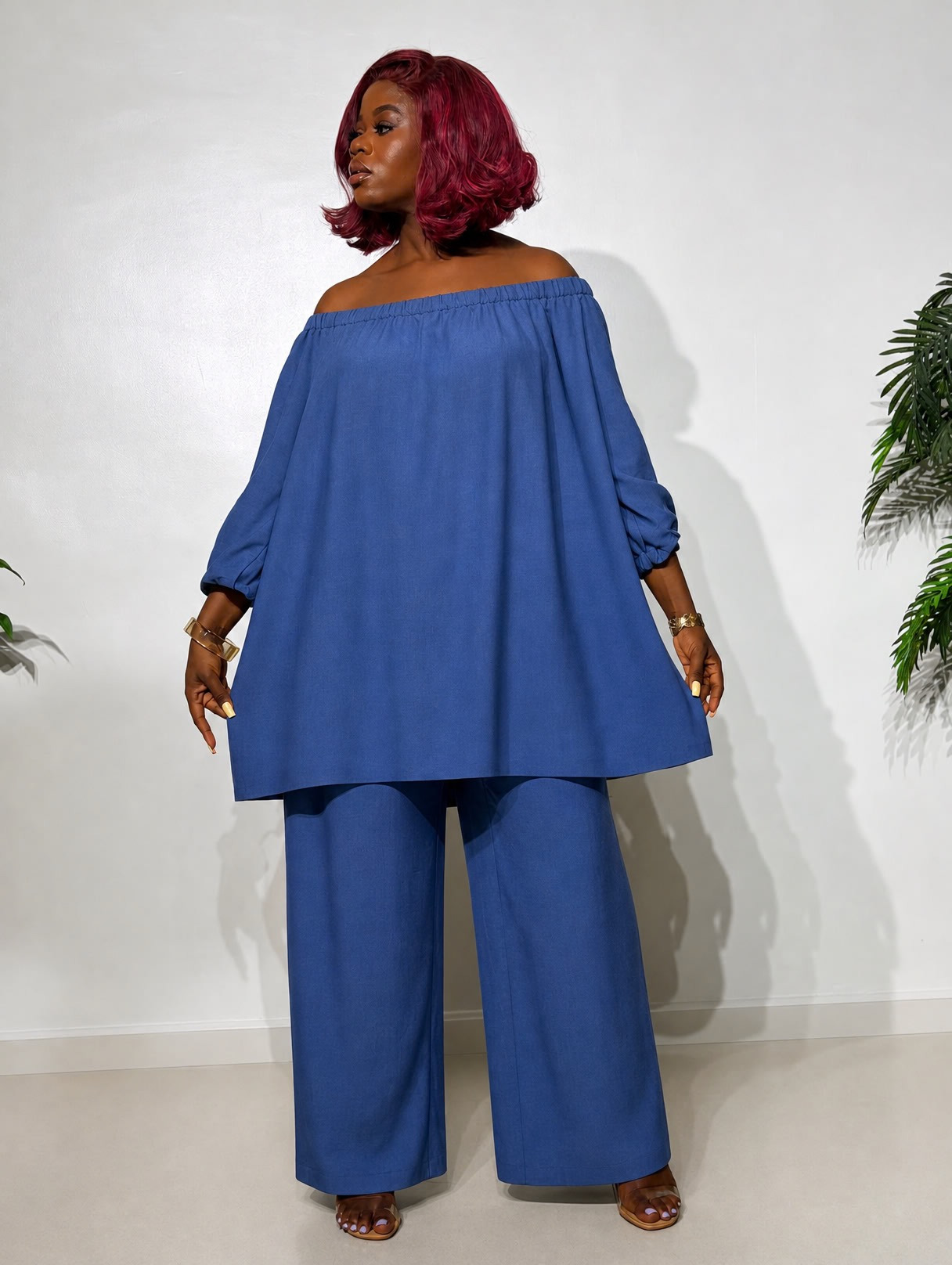 Elegant two-piece outfit featuring an off-shoulder tunic top with statement puff sleeves and matching wide-leg trousers, styled for a classy look.
