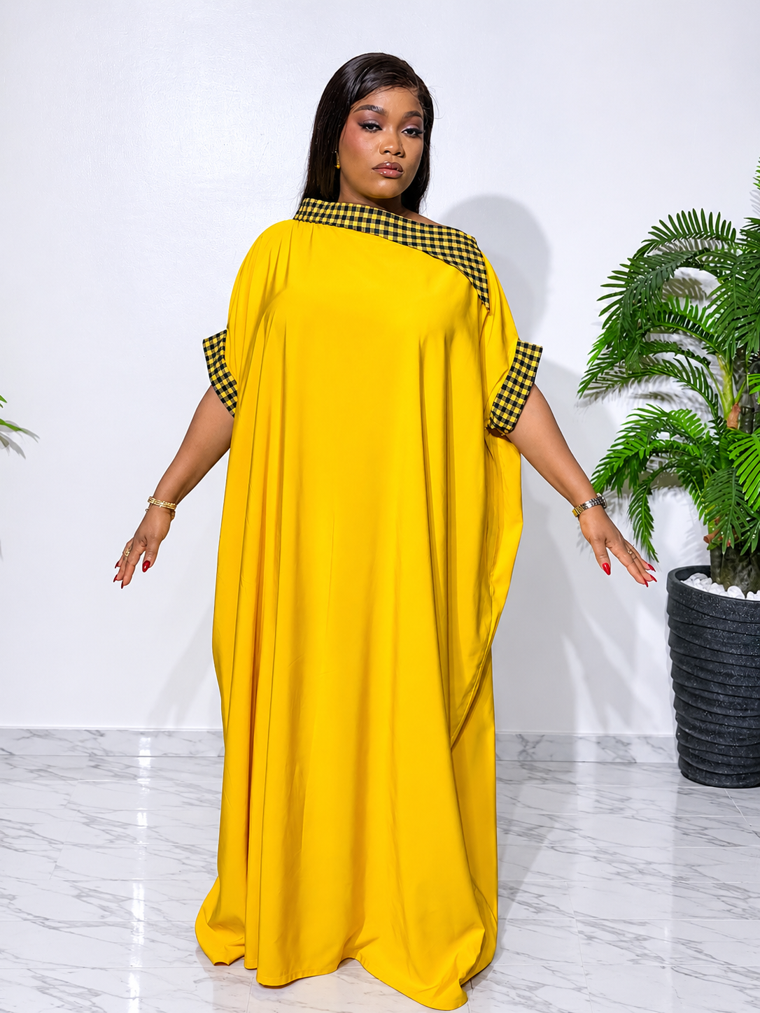 Elegant yellow boubou with yellow-and-white checkered accents, featuring a flowing silhouette, statement cape sleeves, and a luxurious finish.