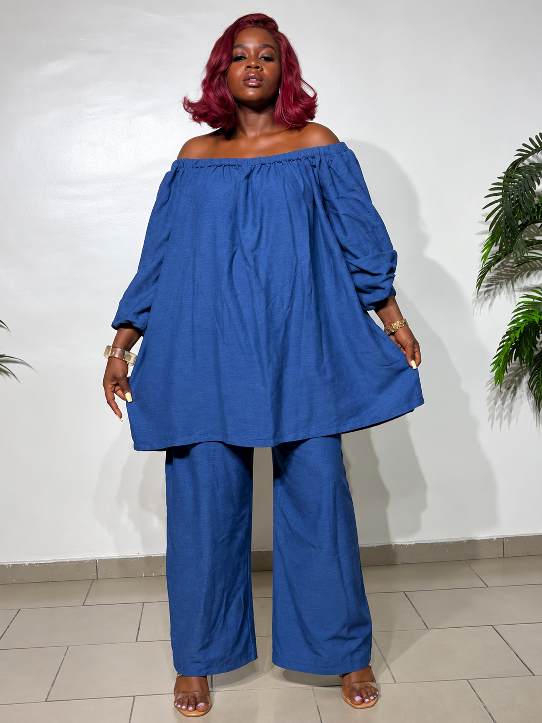 Elegant two-piece outfit featuring an off-shoulder tunic top with statement puff sleeves and matching wide-leg trousers, styled for a classy look.