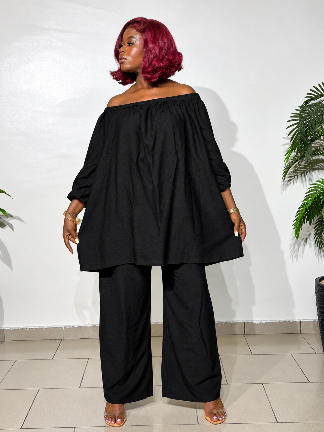 Elegant two-piece outfit featuring an off-shoulder tunic top with statement puff sleeves and matching wide-leg trousers, styled for a classy look.